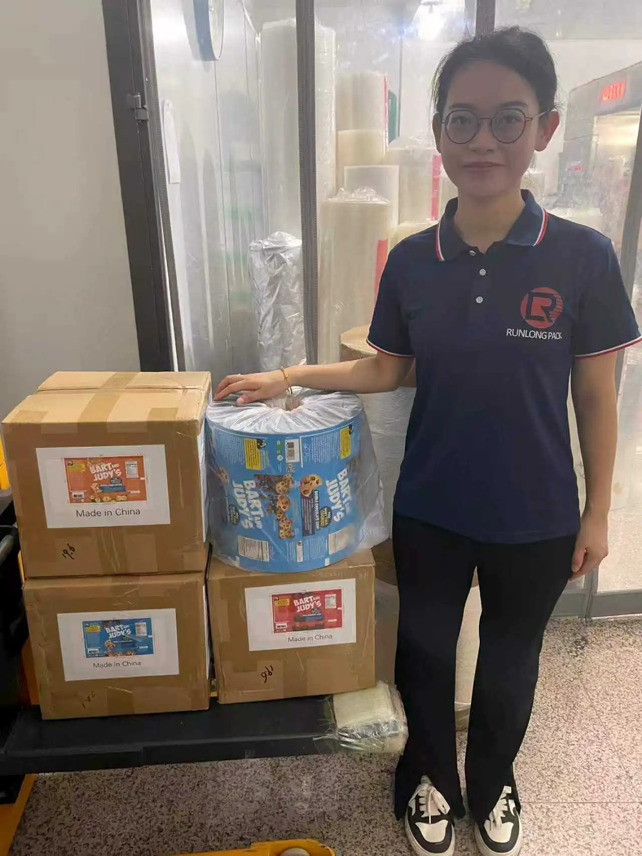 Runlong team member with printed roll film and finished cartons for a U.S. customer project